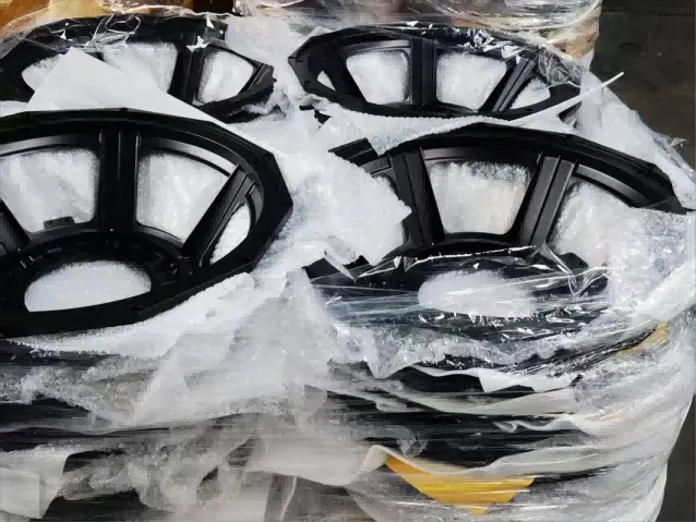 Bulk stock of finished black powder coated aluminum speaker baskets packed on pallets