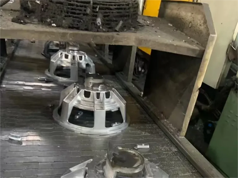 Newly cast raw aluminum speaker baskets on the foundry conveyor belt